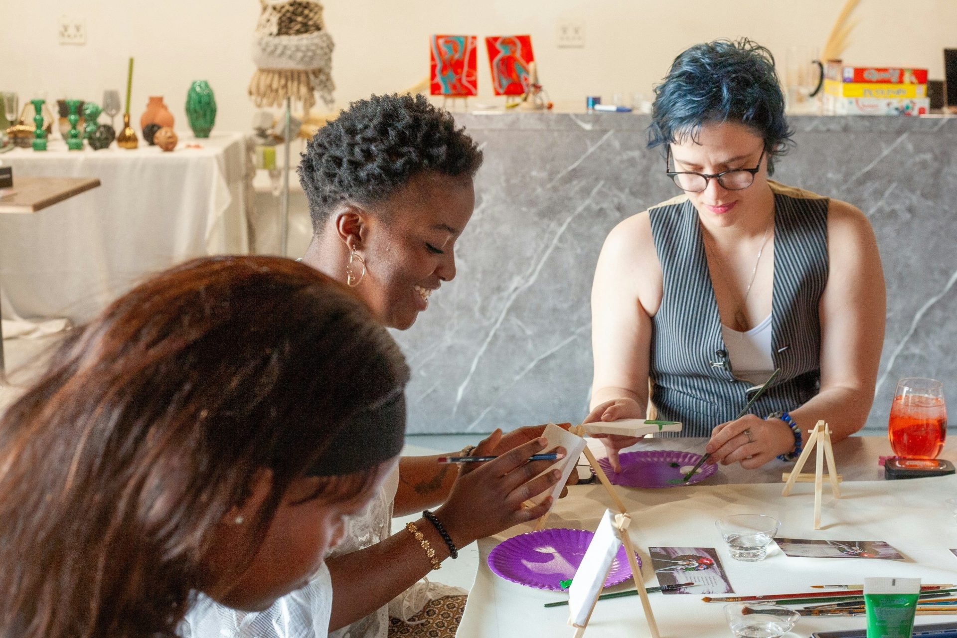 Three women painting and crafting at a table.